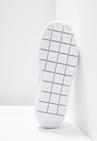 Semelle de chaussure blanche avec un motif en grille de carrés en relief, chacun présentant un petit dessin en forme d'étoile au centre.