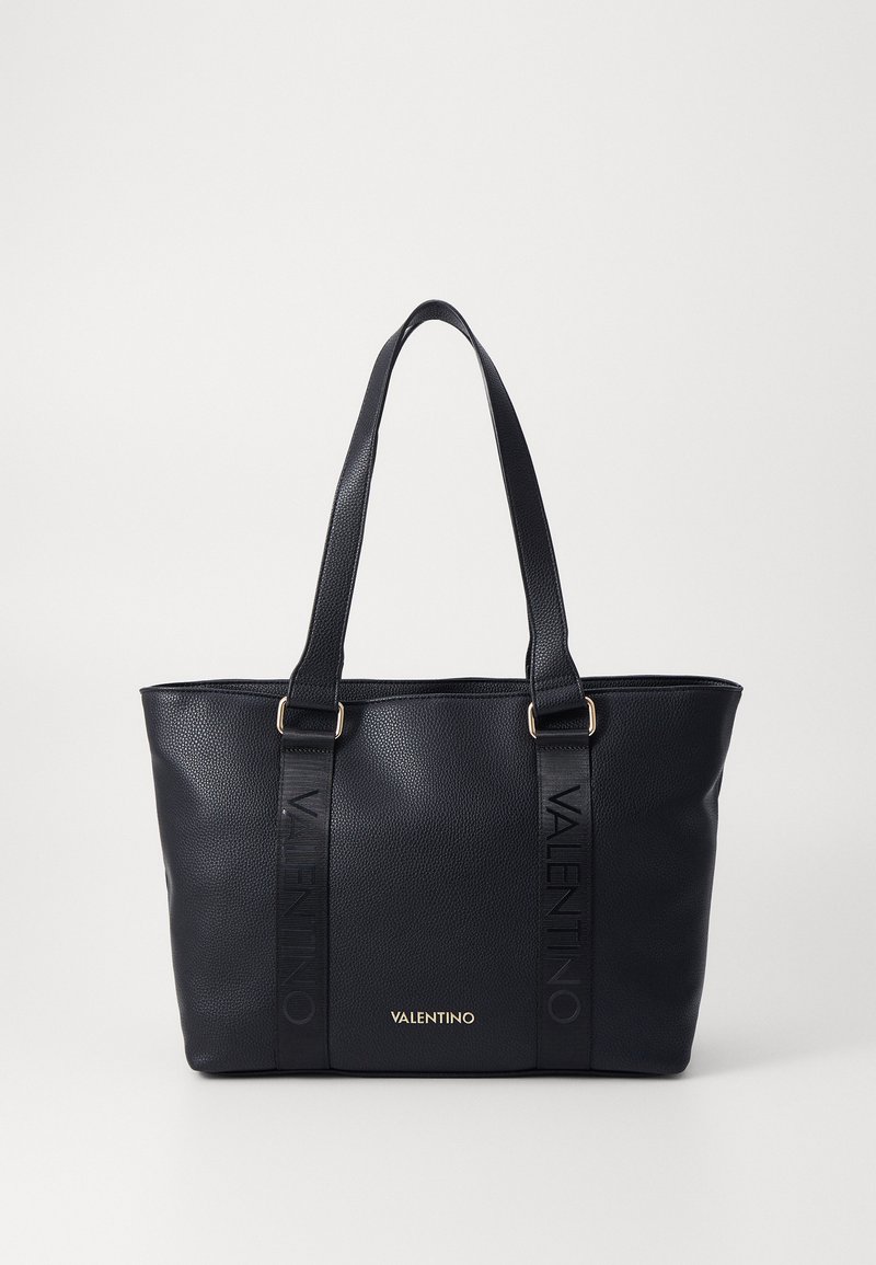 Sort læder tote bag med tekstureret finish, der har to korte håndtag, præget branding på stroppene og guld logo-detail foran.