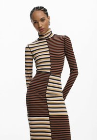 Gestreiftes Langarmkleid mit geripptem Muster in Braun, Schwarz und Beige. Hoher Kragen und figurbetonter Schnitt mit kontrastierenden Paneelabschnitten.