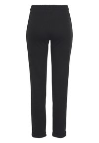 Schwarze Jogginghose mit elastischem Bund, schmaler Passform und umgeschlagenem Saum. Hergestellt aus weichem, glattem Stoff ohne sichtbare Muster oder Akzente.