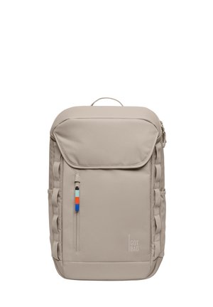 Beige rektangulær rygsæk med topklap, lodret lynlåslomme foran med flerfarvet trækkede flig, sideløkker og "GOT BAG." logo nederst til højre.