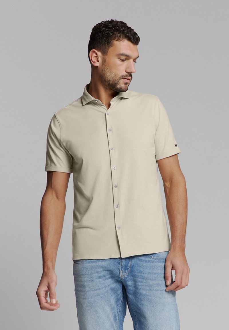 Korte mouwen beige shirt met een kraag, voorzien van een knoopsluiting aan de voorkant en een kleine knoopaccent op de mouw. Gladde textuur van de stof.