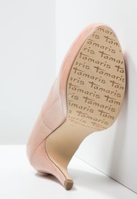 Růžová lodička na vysokém podpatku s hladkým, saténovým svrškem a špičatou špičkou. Podešev zdobí opakující se nápis značky v světle hnědé barvě.