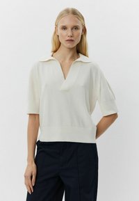 Witte kortemouwen gebreide top met een ribbelstructuur, V-halslijn en een kraag. De zoom is lichtelijk cropped en ontworpen voor een relaxte pasvorm.