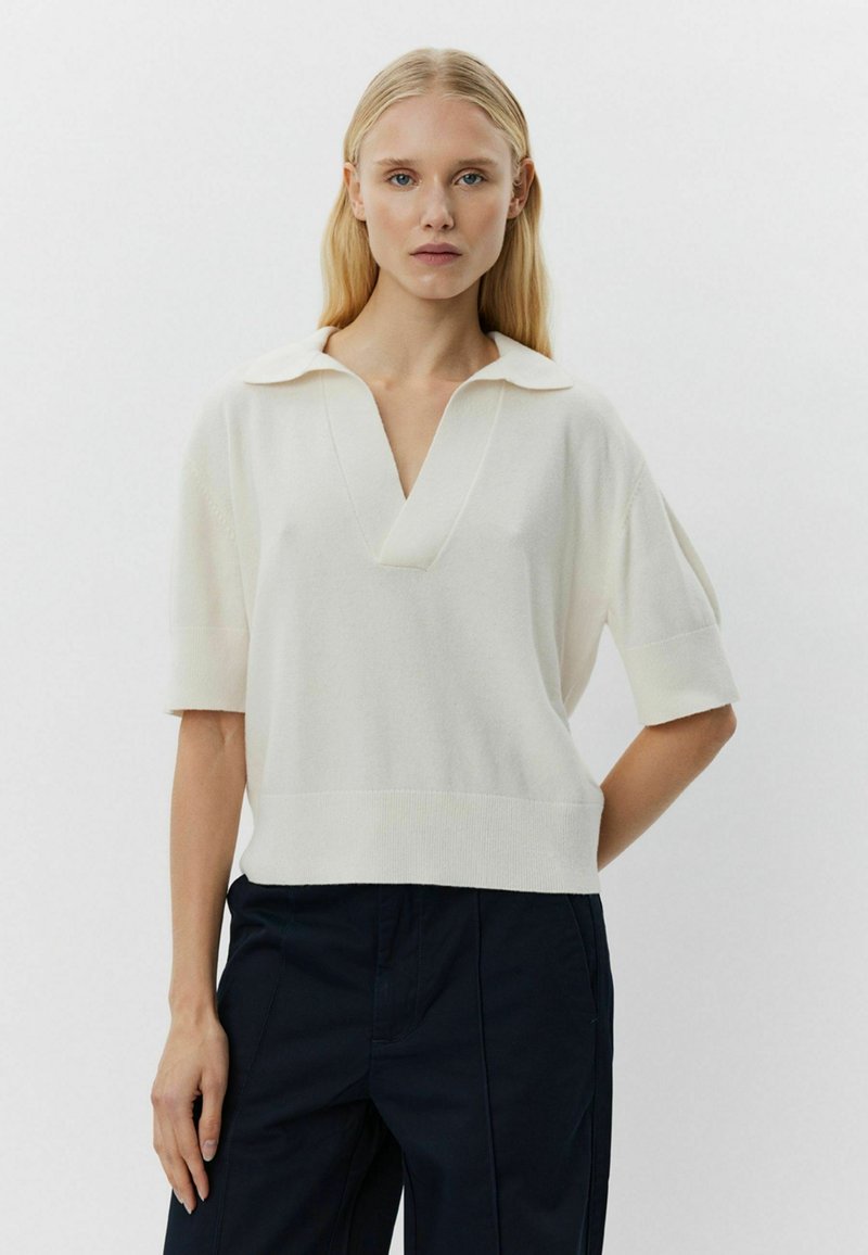 Witte kortemouwen gebreide top met een ribbelstructuur, V-halslijn en een kraag. De zoom is lichtelijk cropped en ontworpen voor een relaxte pasvorm.