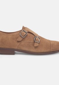 Braune Wildleder-Monk-Schnallenschuhe mit zwei silbernen Schnallen, abgerundeter Zehenform und niedrigem Holzabsatz, mit glatter Textur und minimalen Nähdetails.
