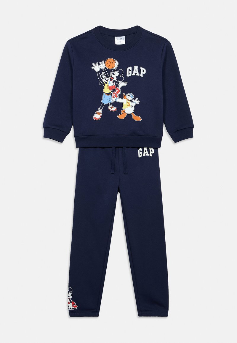 Granatowy dres składający się z bluzy sportowej z okrągłym dekoltem, ozdobionej postaciami z kreskówek oraz logo "GAP", do któregozestawione są pasujące spodnie dresowe z nadrukiem logo.