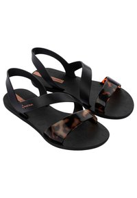 Sandalias de goma negras con una correa de patrón carey. Presentan una suela texturizada y correas superiores cruzadas para soporte y comodidad.