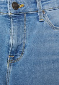 Lichtblauwe denim jeans met een knoopsluiting met merkdetails, gele stiksels en een zichtbare naad van de voorzak.