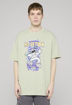 Mladý muž v svetlozelenom tričku s grafikou astronauta držajúceho sprej a textom "NO RETURN" a "GET HIGH".