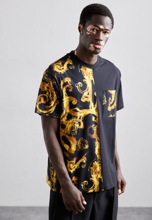 Chemise à manches courtes noire et dorée avec un côté gauche à motifs et un côté droit uni noir, dotée d'une poche poitrine et d'une coupe décontractée.