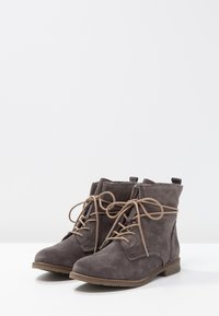 Botines de ante gris con puntera redondeada, que presentan un diseño clásico de cordones y una suela baja y plana. Acabados con costuras sencillas y una tira en la parte posterior.