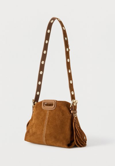 Καφέ τσάντα από σουέτ με στρογγυλεμένο σχήμα, διακοσμητικό κρόσσι στην πλευρά και λουρί σε αντίθεση με κυκλικά διακοσμητικά στοιχεία. Λεπτομέρειες σε χρυσή απόχρωση.