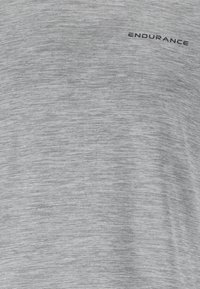 Graues Sport-T-Shirt aus strukturiertem Stoff mit horizontalen Streifen und einem schwarzen "ENDURANCE"-Logo, das oben links aufgedruckt ist.