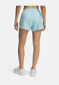 Pantalones cortos deportivos azul claro con cintura elástica, con una textura suave y un ajuste holgado, combinados con zapatillas blancas.