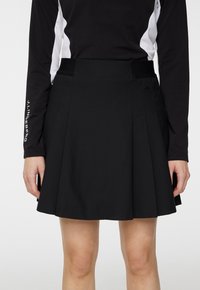 Czarna plisowana spódnica wykonana z lekkiego materiału, o gładkiej fakturze i regulowanym pasku w talii z bocznymi kieszeniami.