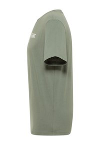 Zaļš kokvilnas T-krekls ar īsām piedurknēm, apaļu kakla izgriezumu un uzdrukātu tekstu priekšpusē. Gluda tekstūra, ikdienas piegriezums.