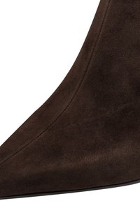 Ruskean nubukka korkeakorkoiset kengät, joissa on terävä kärki ja sileä pinta. Ominaisuuksiin kuuluu saumatön muotoilu ja hoikka, ylöspäin kaartuva kaari.