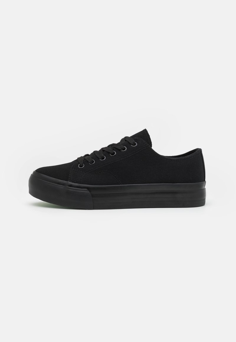 Black canvas sneakers with round toe, six eyelets, flat laces, and rubber sole. Smooth texture with no visible patterns or accents.