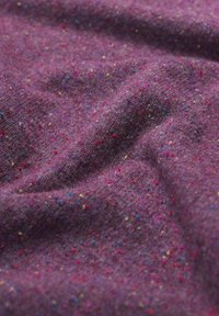 Violeta audums ar mīkstu, teksturētu virsmu, kurā ir daudzkrāsaini plankumi, kas izkaisīti visā, radot dzīvīgu rakstu.