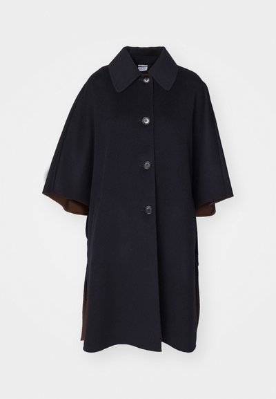 Cappotto in misto lana nero con ampio colletto, dotato di chiusura frontale a bottoni e maniche corte. Le fessure laterali rivelano un rivestimento marrone.