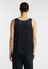 Top in satin blu navy con vestibilità rilassata, scollatura rotonda e orlo pulito. Progettato senza decorazioni o fantasie.