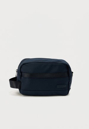 Compact navy blue toiletry bag with black handle strap and a front zipper pocket, branded with a small GANT logo patch.