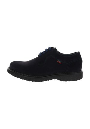 Scarpa da uomo stringata in camoscio nero con tacco basso, punta arrotondata, suola testurizzata e discreta etichetta del marchio blu e rossa sul lato.