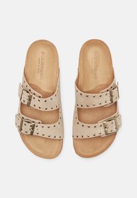 Sandali in camoscio beige con due cinturini con fibbia e piccoli borchietti metallici, suola piatta, con etichetta interna "Scarosso Made in Italy".