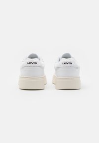 Zapatillas blancas con parte superior de cuero liso, suela de goma crema y el logotipo negro "Levi's" en el talón. Diseño de punta redondeada.