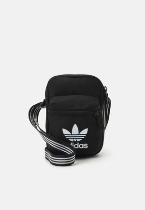 Schwarze Adidas Crossbody-Tasche mit vorderer Reißverschlusstasche und weißem Trefoil-Logo, mit verstellbarem schwarzen Riemen mit weißen Streifen.