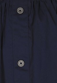 Mørkeblå stof med en glat overflade. Har en vertikal stolpe med tre grå knapper i midten. Enkel design uden mønstre.