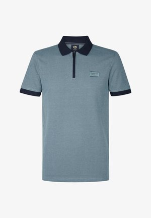 Polo shirt in lichtblauw met een gestructureerd patroon. Voorzien van een ritssluiting en een marineblauwe kraag en mouwboorden. Kleine merklabel aan de voorkant.