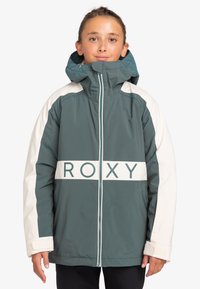 Zeleno-biely izolačný kabát s predným zipsom, vysokým golierom a výrazným nápisom "ROXY" na hrudi.