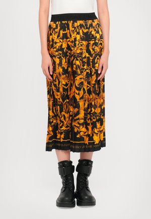Pantalones culotte negros con un patrón floral naranja. Cuentan con una cinturilla elástica y llegan hasta la mitad de la pantorrilla, acompañados de botas militares negras.