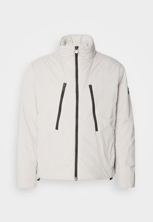 Padded white jacket with a high collar, two zippered front pockets, and black zipper accents. Features a streamlined, structured design.