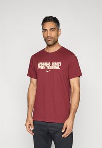 Μπορντό μπλουζάκι με το σύνθημα "Η ΝΙΚΗ ΑΡΧΙΖΕΙ ΜΕ ΤΗΝ ΠΡΟΠΟΝΗΣΗ" σε εκρού γράμματα. Κατασκευασμένο από μαλακό βαμβάκι, με κοντά μανίκια και στρογγυλή λαιμόκοψη.