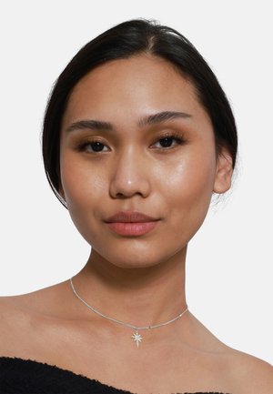 Choker en argent avec un pendentif en forme d'étoile, doté d'une chaîne délicate et d'une finition lisse et polie. Design simple et élégant.