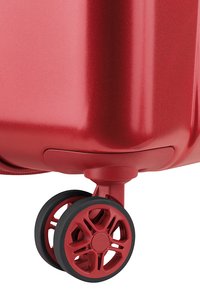 Valigia rigida rossa con una finitura liscia e lucida e un design delle ruote neri a più raggi per la mobilità. Presenta una forma aerodinamica.