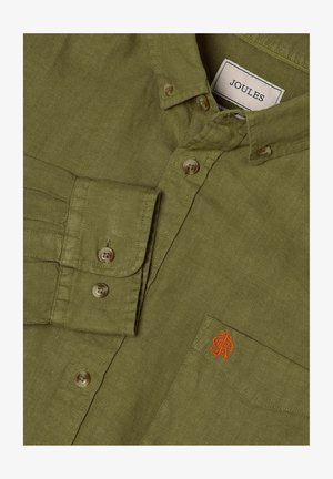 Chemise en lin vert olive à boutons, col boutonné, poche avant avec petit logo orange brodé, et étiquette Joules de marque à l'intérieur du col.