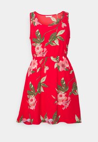 Robe rouge sans manches avec un motif floral comprenant des fleurs roses et des feuilles vertes. Tissu doux, taille élastique, jupe évasée.