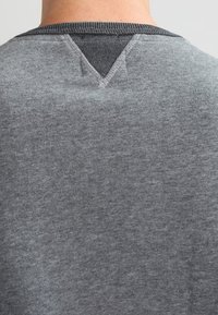 Grauer Sweatshirt mit strukturierter Stoffoberfläche, V-förmigem Rückenausschnitt und kontrastierendem, dunklem Kragen. Einfaches, zeitgemäßes Design.