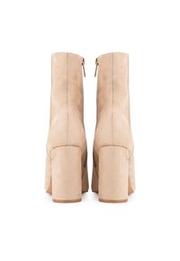 Bottes beige en daim à cheville avec un bout carré, un talon bloc haut et un détail de fermeture éclair dorée à l'arrière. Présente une couture minimale pour un design épuré.