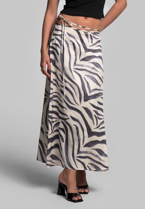 Gonna maxi in tessuto leggero con base crema e audaci strisce zebra nere. Presenta una fessura laterale e un dettaglio con cintura annodata.