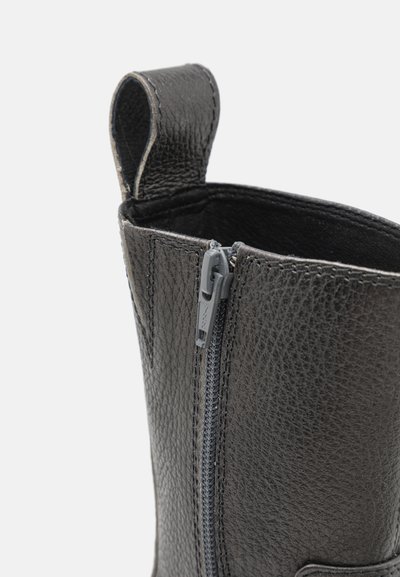 Stivale in pelle nera con superficie testurizzata, chiusura a zip e una piccola asola per una facile estrazione. Il design è a metà caviglia e slanciato.