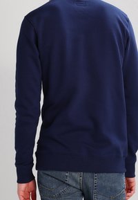 Sweat-shirt bleu marine, en coton, manches longues, poignets et ourlet côtelés, design simple sans motifs ni accents visibles.