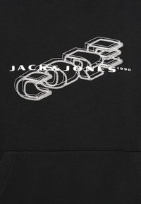 Svart sweatshirt med fet vit grafisk text "JACK & JONES 1990" i ett lagerat, 3D-liknande mönster. Mjuk textur med en framficka.