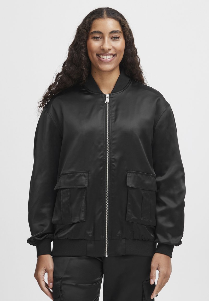 Jachetă bomber din satin negru, cu fermoar frontal, două buzunare frontale cu clapetă, manșete ribbate și talie ajustată. Textură netedă cu un design elegant.