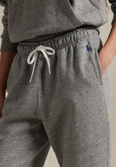 Grijze sweatpants van zacht materiaal, met een elastische tailleband met trekkoord en zijzakken. Klein blauw logo detail op het been.