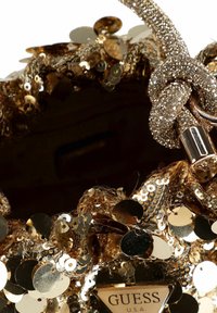 Borsa color oro con paillettes e superficie texturizzata, caratterizzata da una tracolla decorativa lucida e un'etichetta con logo triangolare alla base. La chiusura è ad apertura superiore.